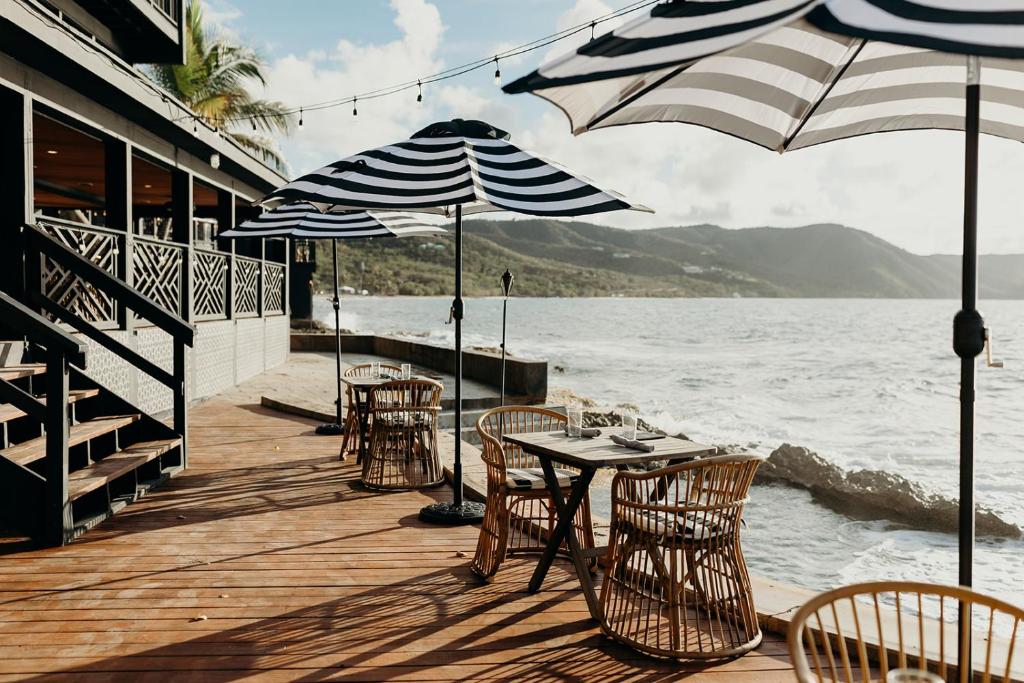 a wooden deck with tables and chairs and umbrellas at The Waves at Cane Bay in Kingshill