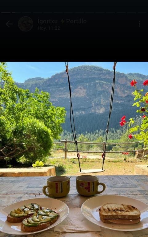 a table with two plates of food and two cups at Casas Rurales El Portillo in Yeste