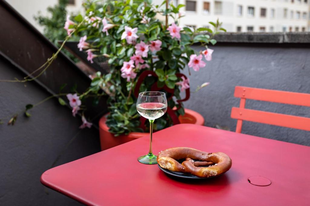 un verre de vin et un bretzel sur une table rouge dans l'établissement Le Balcon fleuri centre Robertsau tram Jardiniers, à Strasbourg