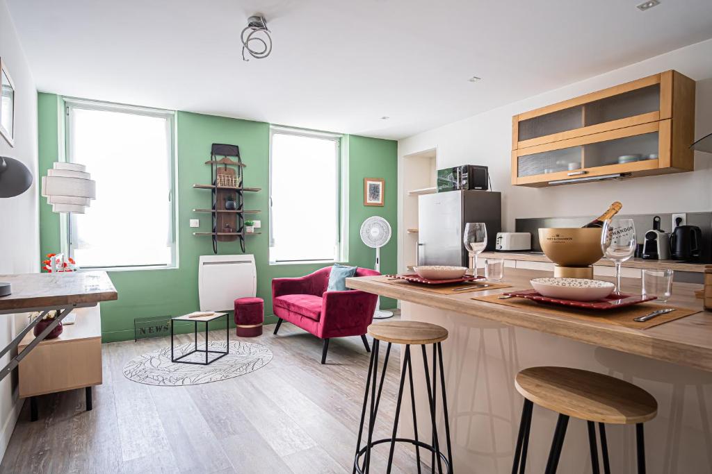 une cuisine aux murs verts et un comptoir avec tabourets de bar dans l'établissement Elegant Apartment City center Cathedral, à Reims