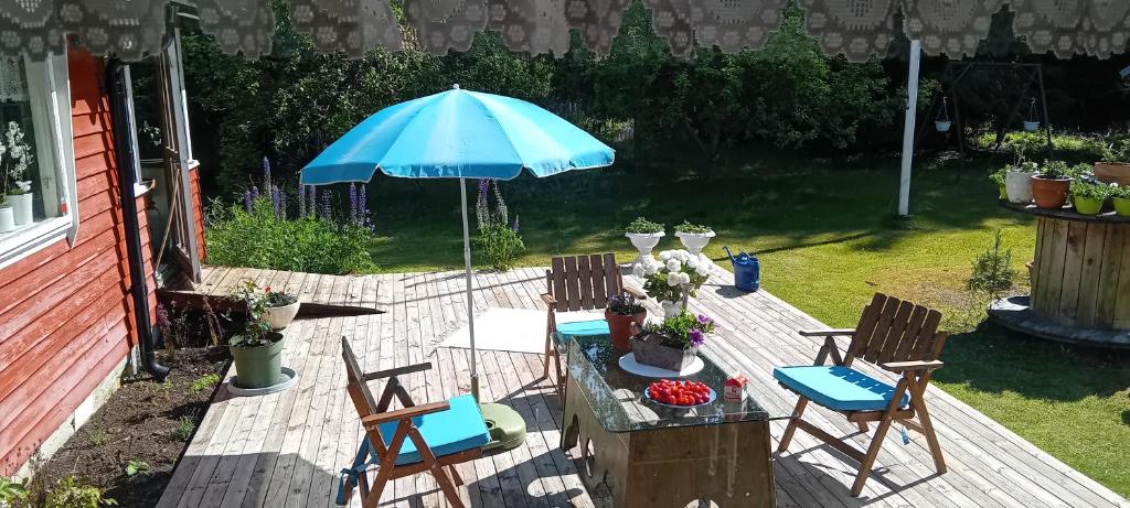 a patio with a table and a blue umbrella at Strandvikstugan in Väse