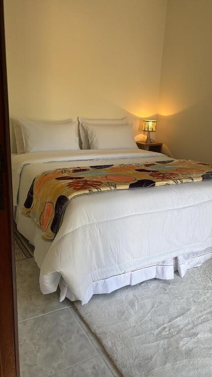 a bedroom with a large bed with white sheets at Casa Refúgio Canto da Viola in São Roque