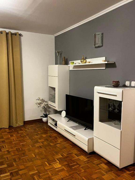 a living room with a tv and a white entertainment center at Apartman Nada in Biograd na Moru