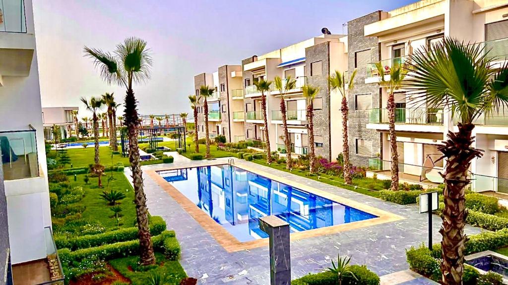 an apartment complex with a swimming pool and palm trees at Garden Bay Luxe, Tamaris Bord de Mer in Casablanca