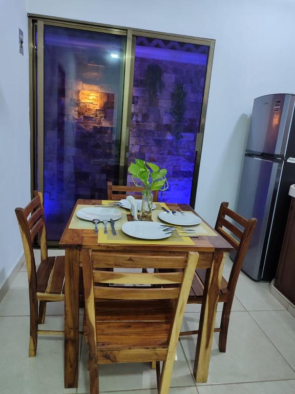 a wooden table with two chairs and a table with plates on it at Chan Kiin Departamentos in Valladolid