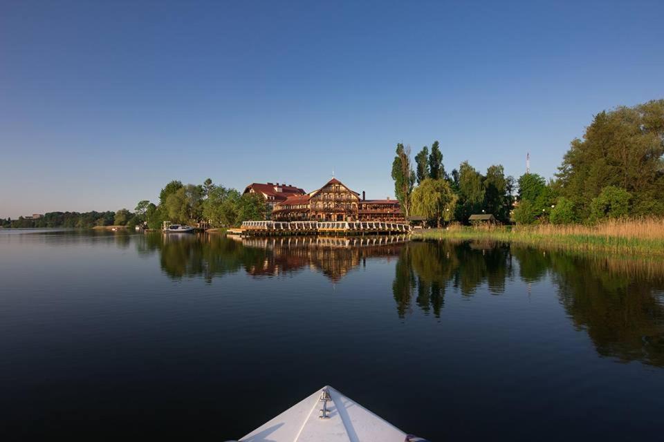 a boat on a lake with a large building at Gościniec Molo in Mrągowo