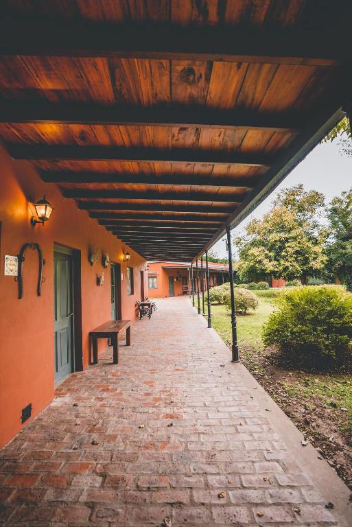 a brick walkway with a wooden roof on a building at Puesto Viejo in Cañuelas