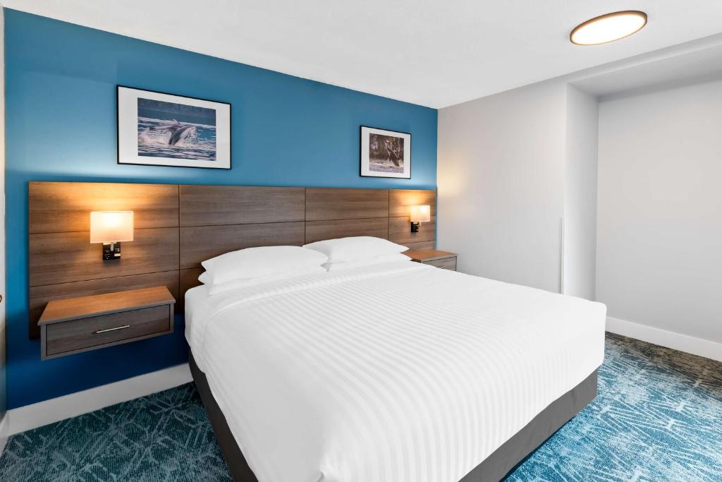 a bedroom with a large white bed with a blue wall at Hotel Feng, BW Signature Collection in Parksville