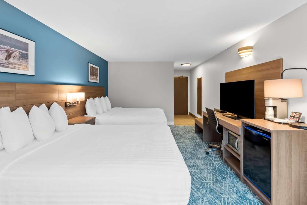a hotel room with two beds and a flat screen tv at Hotel Feng, BW Signature Collection in Parksville