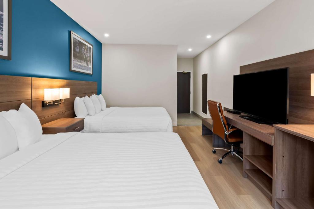 a hotel room with two beds and a desk with a computer at Hotel Feng, BW Signature Collection in Parksville