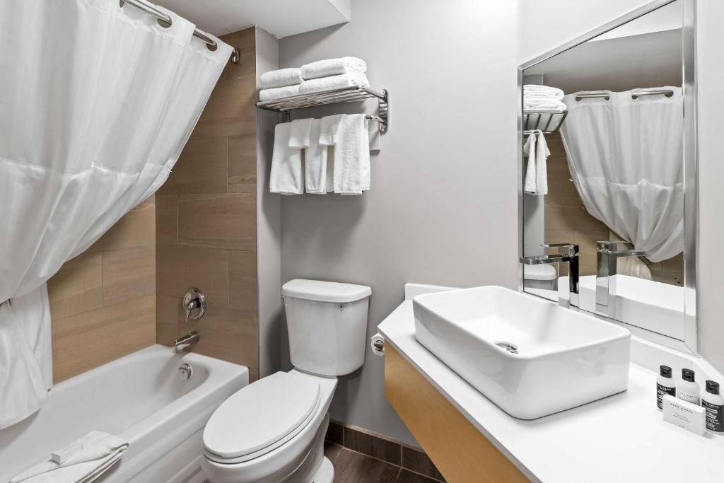 a white bathroom with a toilet and a sink at Hotel Feng, BW Signature Collection in Parksville