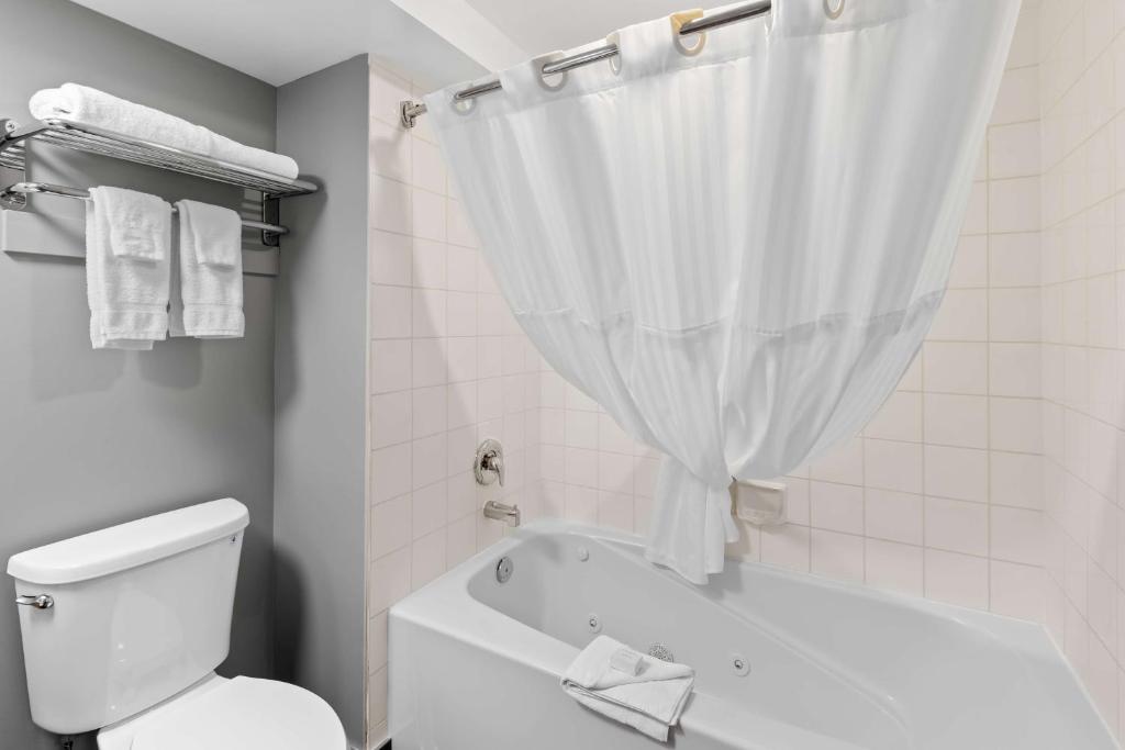 a white bathroom with a toilet and a bath tub at Hotel Feng, BW Signature Collection in Parksville