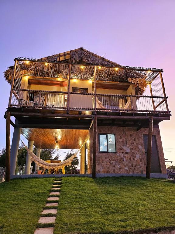a house with a deck on top of a lawn at Chalé Duplex Beira Mar Macapá in Luis Correia