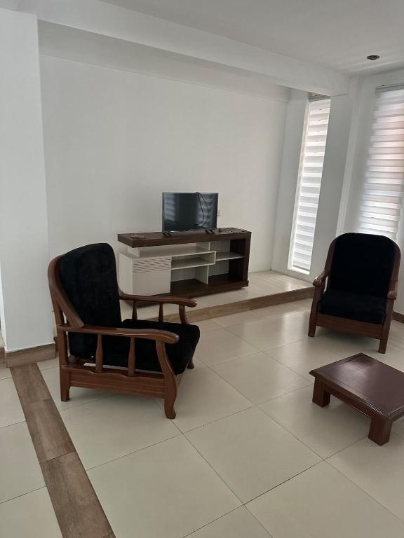 a living room with two chairs and a tv at Beautiful house downtown in Tarija