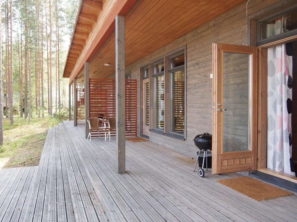 a wooden porch of a house with a grill on it at Kuoreksenniemi Villas & Lakehouse in Puumala