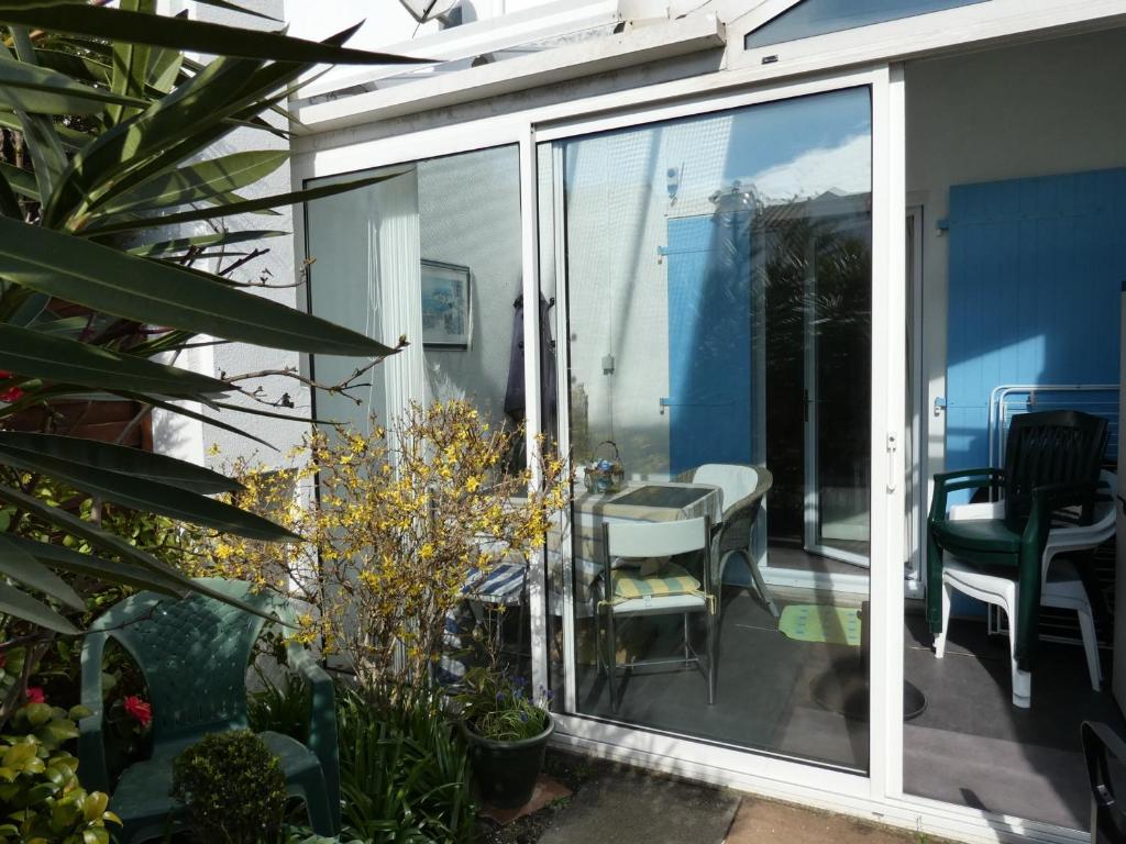 une porte coulissante en verre menant à une terrasse avec une table et des chaises. dans l'établissement Charmante maison à 400m de la plage des Demoiselles avec véranda et cour close - FR-1-323-367, à Saint-Hilaire-de-Riez