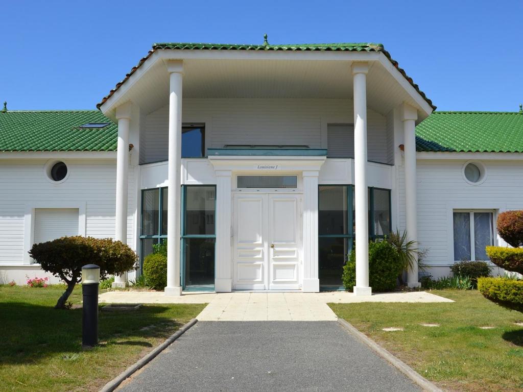 une maison blanche avec une porte et des colonnes blanches dans l'établissement Appartement Spacieux - 3 Chambres - Proche Plage et Golf avec Piscine - FR-1-323-487, à Saint-Jean-de-Monts