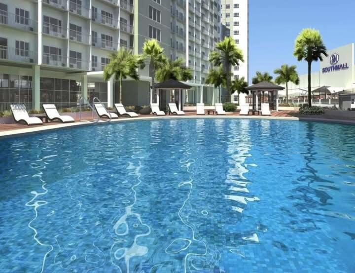 a large swimming pool with chairs and a building at South Residence Condo Las Pinas, Manila in Manila