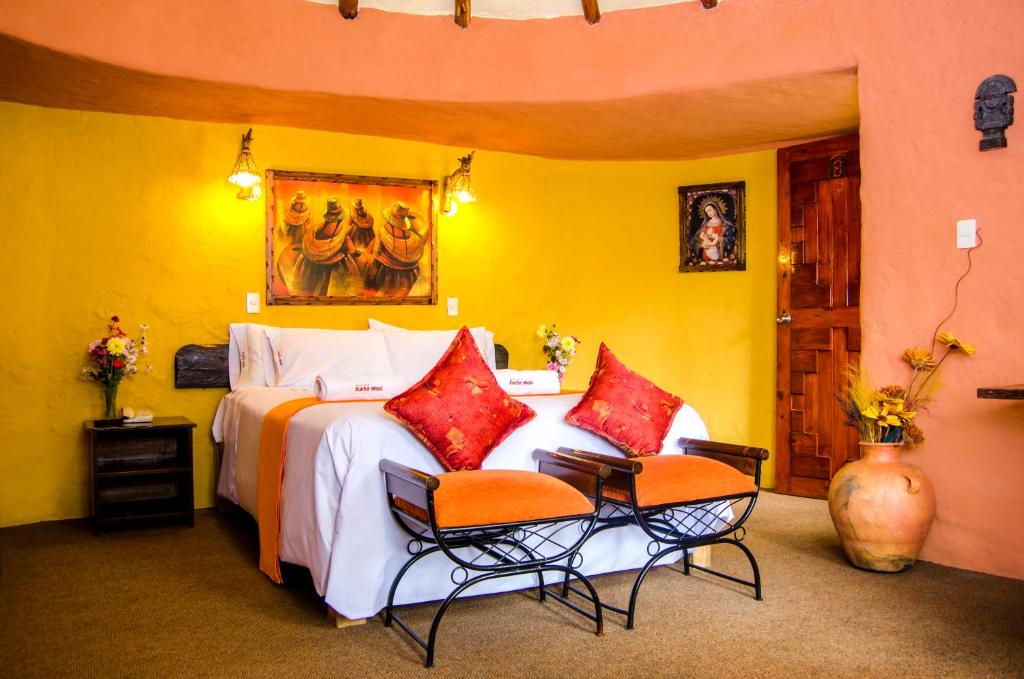 a bedroom with a large bed with two chairs at Hotel Kuntur Wassi in Cabanaconde