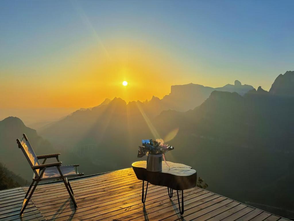 a table and a chair on a deck with a sunset at Cloudspire Haven in Zhangjiajie