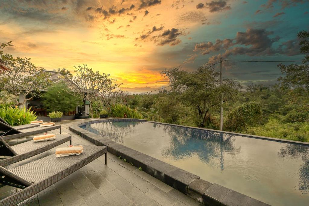 a swimming pool with a sunset in the background at WK Penida Cottage in Nusa Penida