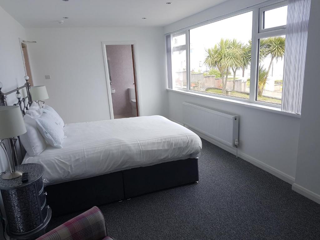 a white bedroom with a bed and a window at Halfway House Hotel in Larne