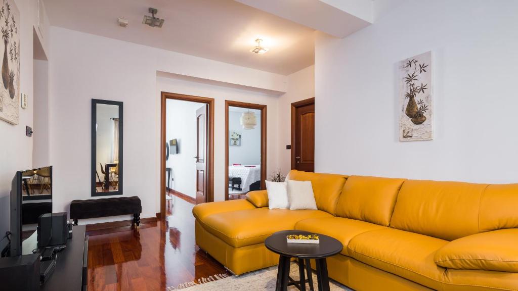 a living room with a yellow couch and a table at Suite Celebration in Split