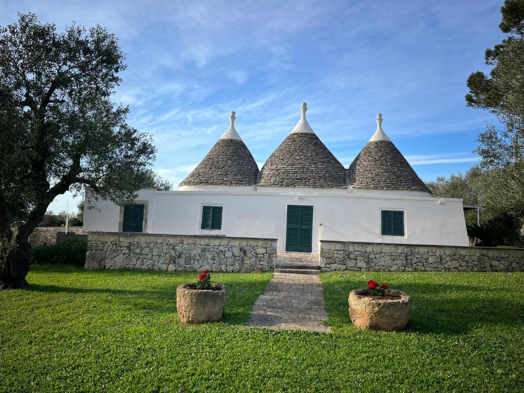 a large white building with pointed roofs with two baskets at Trulli Capomazza in Noci