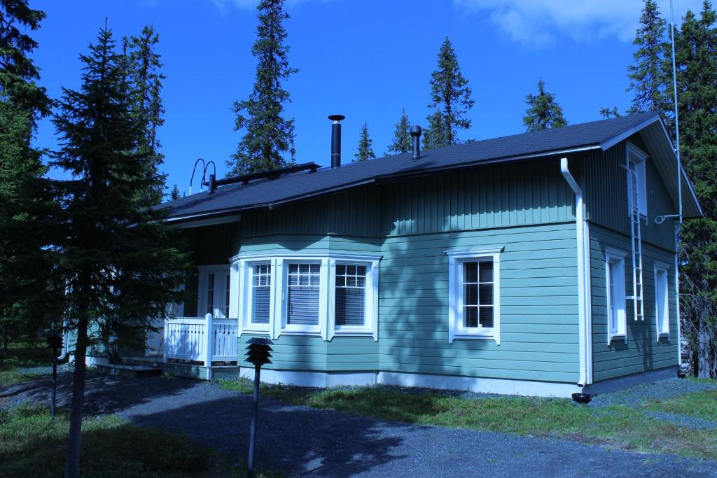 a small green house with a porch at Rukan Mökit in Ruka