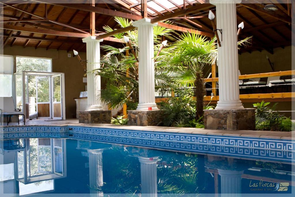 una piscina con dos columnas y una casa en Cabañas y Spa Las Pircas en Tandil