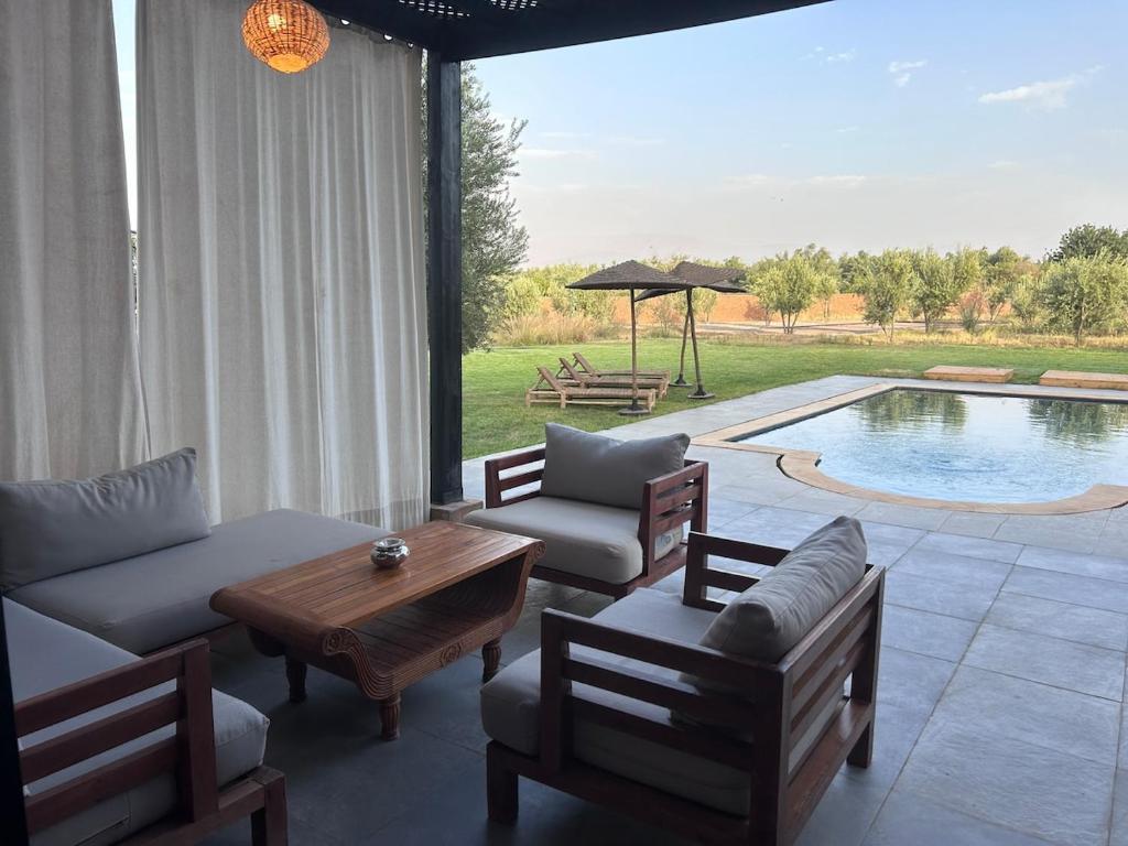 uma sala de estar com mesa e cadeiras e uma piscina em Un havre de paix à Marrakech em El Aggada