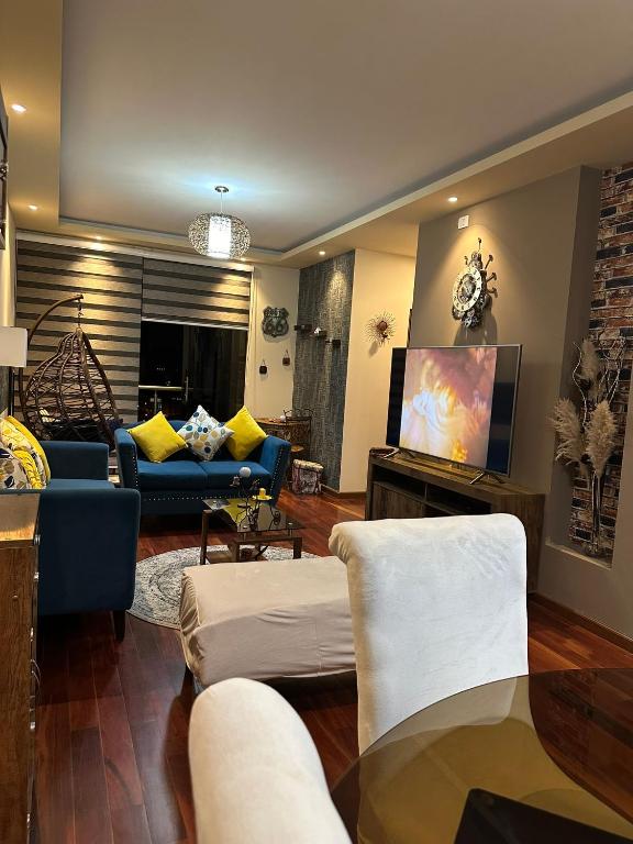 a living room with a blue couch and a tv at Departamento de lujo domotizado en la mejor zona de Cochabamba, frente al Paseo Aranjuez in Cochabamba