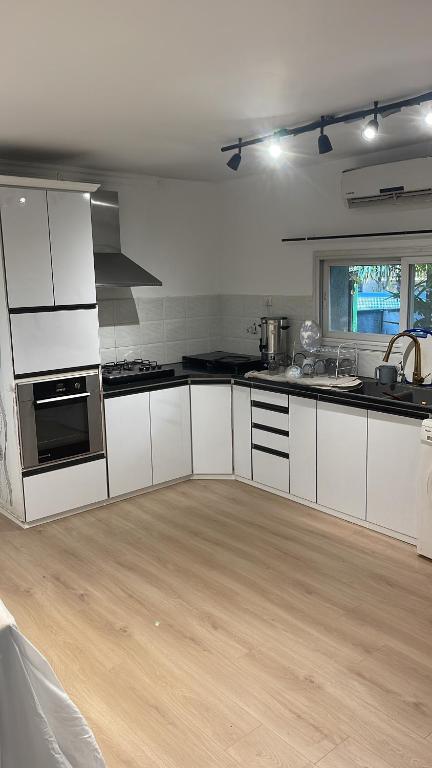 a kitchen with white cabinets and a wooden floor at הוילה הצפונית in Kefar Zetim