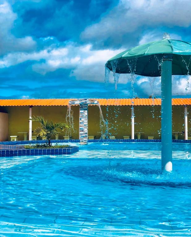 a swimming pool with an umbrella in the water at Pousada e Restaurante Vale Verde in Cabaceiras