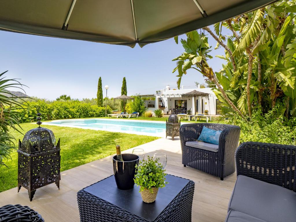 a patio with chairs and a table and a pool at Cubo's Casa Rural El Oasis De Don Pedro in Villafranco de Guadalhorce