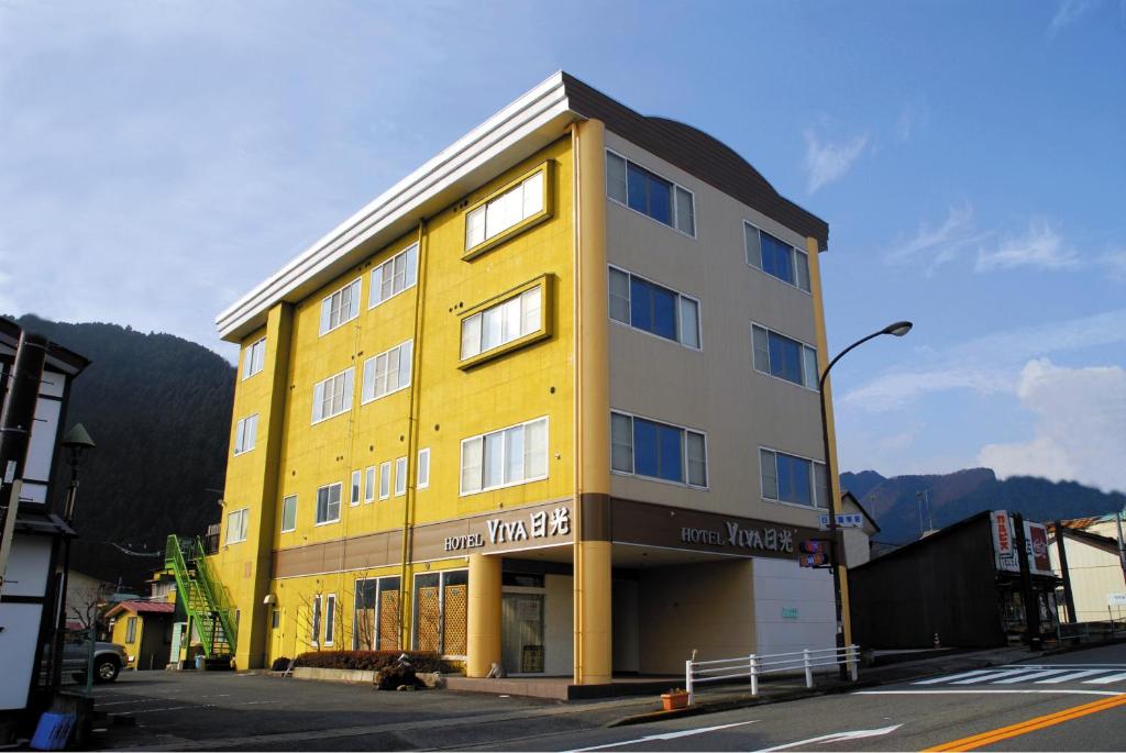 un edificio amarillo y gris al lado de una calle en Hotel Viva Nikko, en Nikko