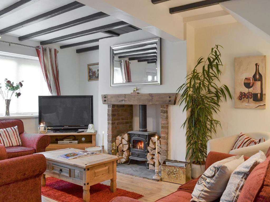 a living room with a fireplace and a tv at Church Court Cottage in Beeford