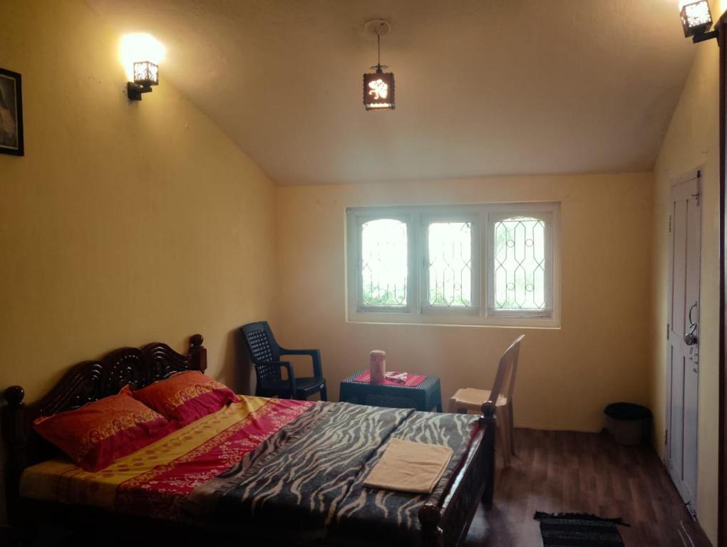 a bedroom with a bed and a window at Kodai Queen Homestay in Kodaikānāl