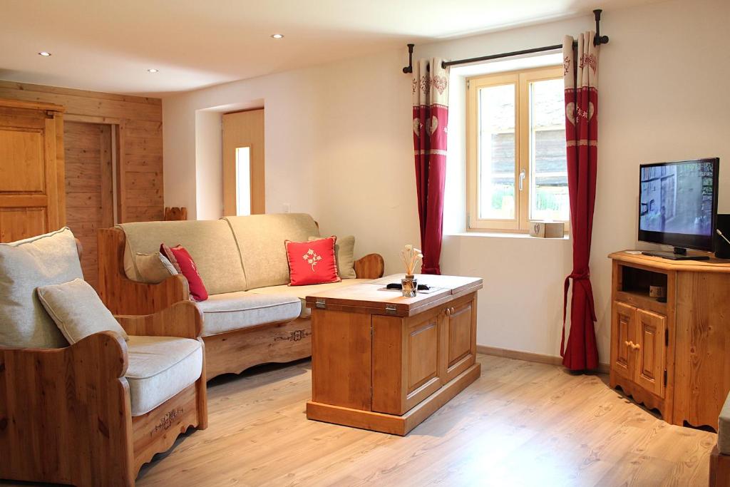a living room with a couch and a tv at Bon Repos - Cosy avec terrasse Evolene in Evolène