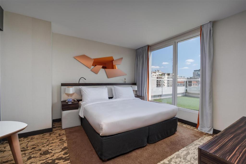 Una habitación de hotel con una cama y una ventana grande. en Radisson Blu Hotel, Paris Boulogne, en Boulogne-Billancourt