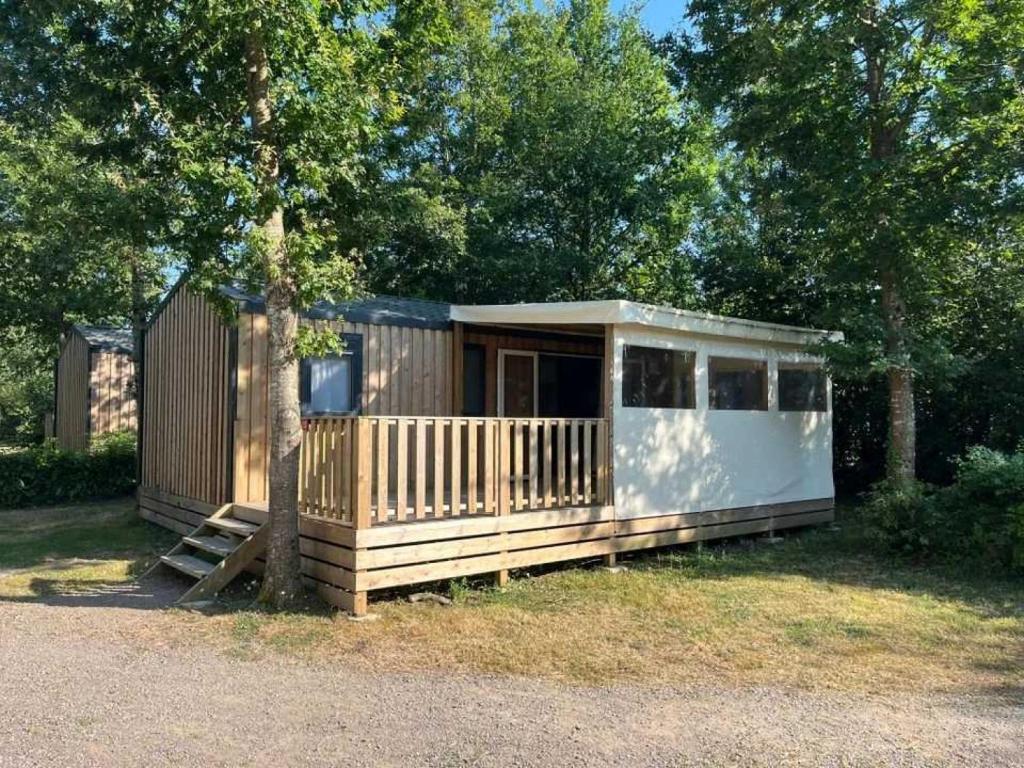 une petite maison avec une véranda et un arbre dans l'établissement Camping 4 étoiles - Piscine - eehi00, à Aubigny