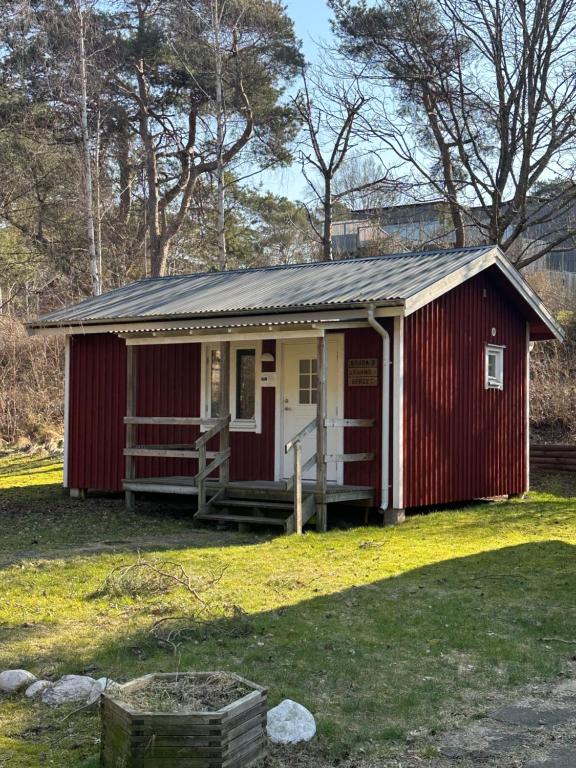 un abri rouge et blanc avec une véranda dans l'établissement Kolonin Kuggaviken, à Åsa