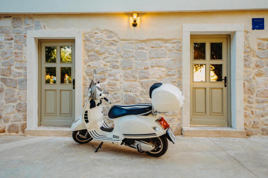 a white scooter parked in front of a stone building at Tramontana Iž in Veli Iž