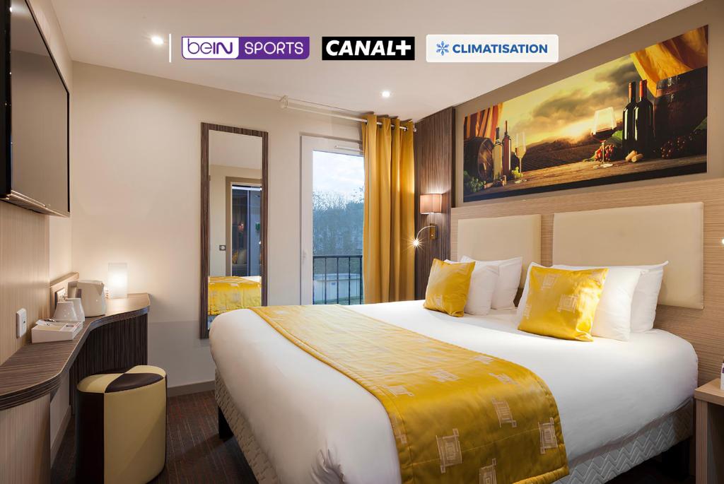 ein Hotelzimmer mit einem großen Bett mit gelben Kissen in der Unterkunft Comfort Hotel Orléans Olivet Provinces in Olivet