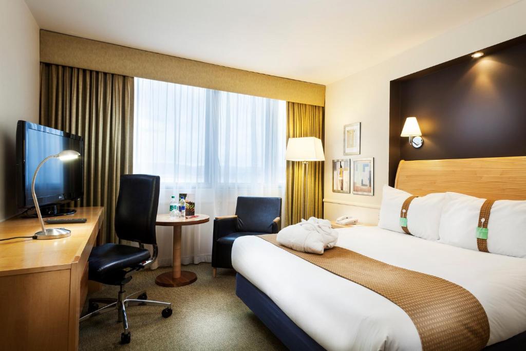 a hotel room with a bed and a desk and a television at Holiday Inn - Glasgow Airport by IHG in Paisley