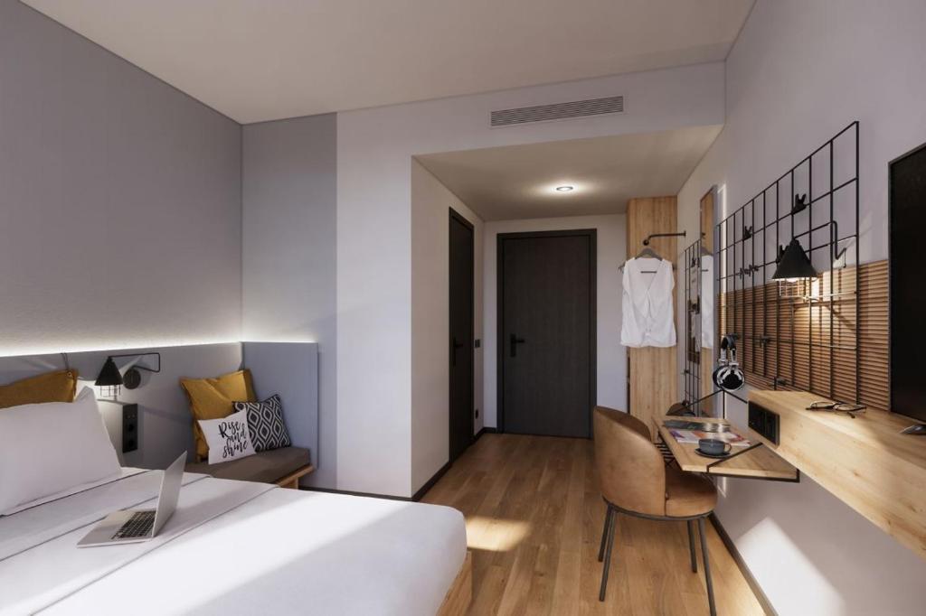 a hotel room with a bed and a desk at Moxy Alfragide Lisboa in Alfragide