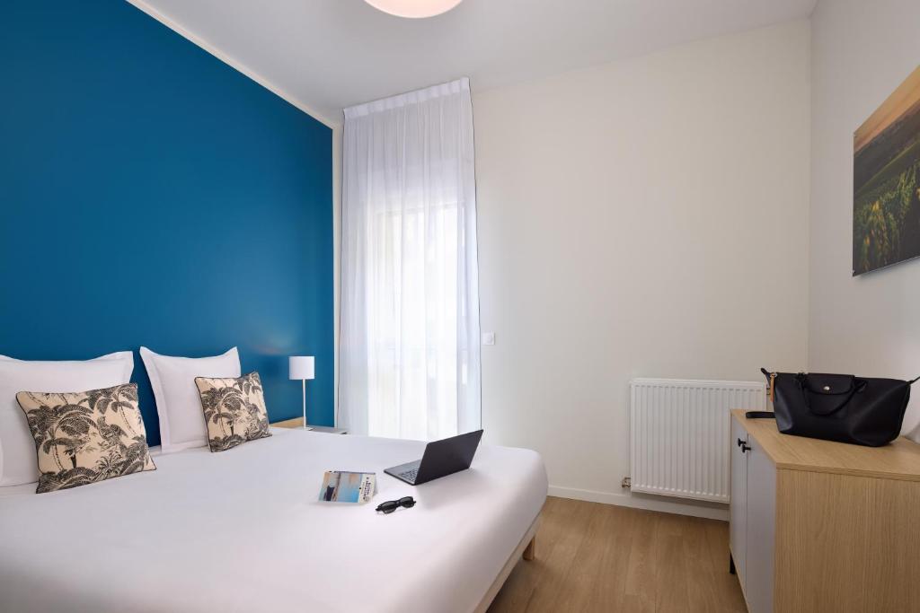 a bedroom with a white bed with a laptop on it at Zenitude Hôtel-Résidences Bordeaux Saint-Jean in Bordeaux
