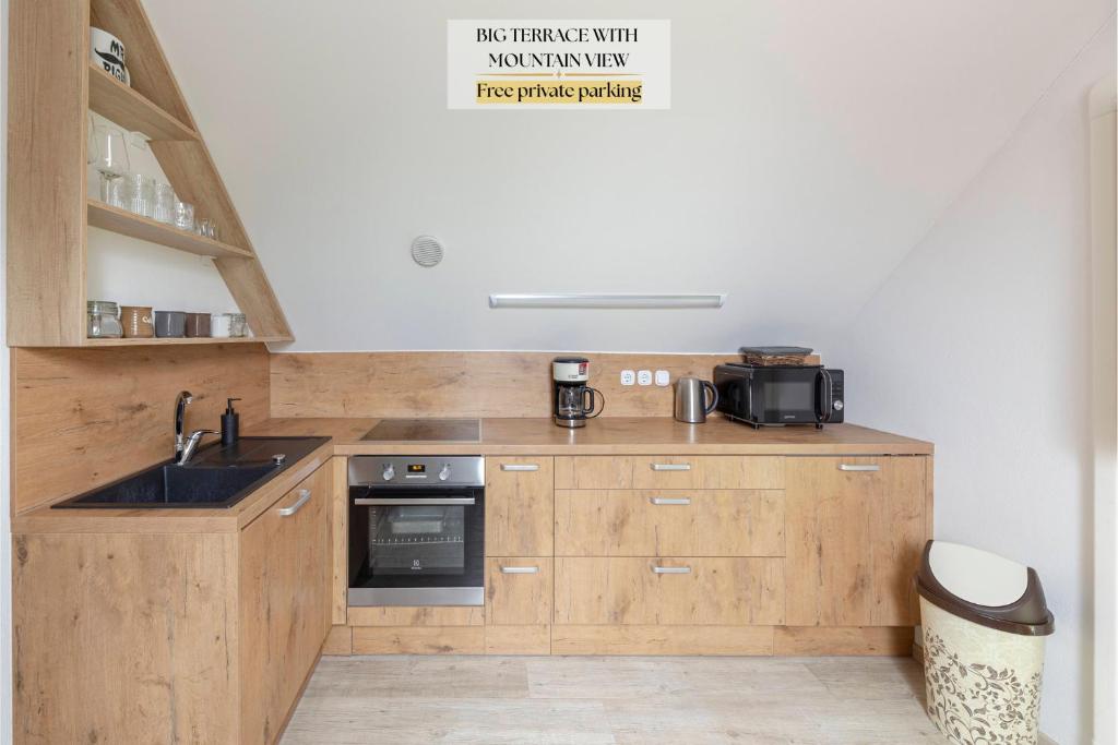 a kitchen with wooden cabinets and a sink at APARTMA KOŠNIK in Bohinj