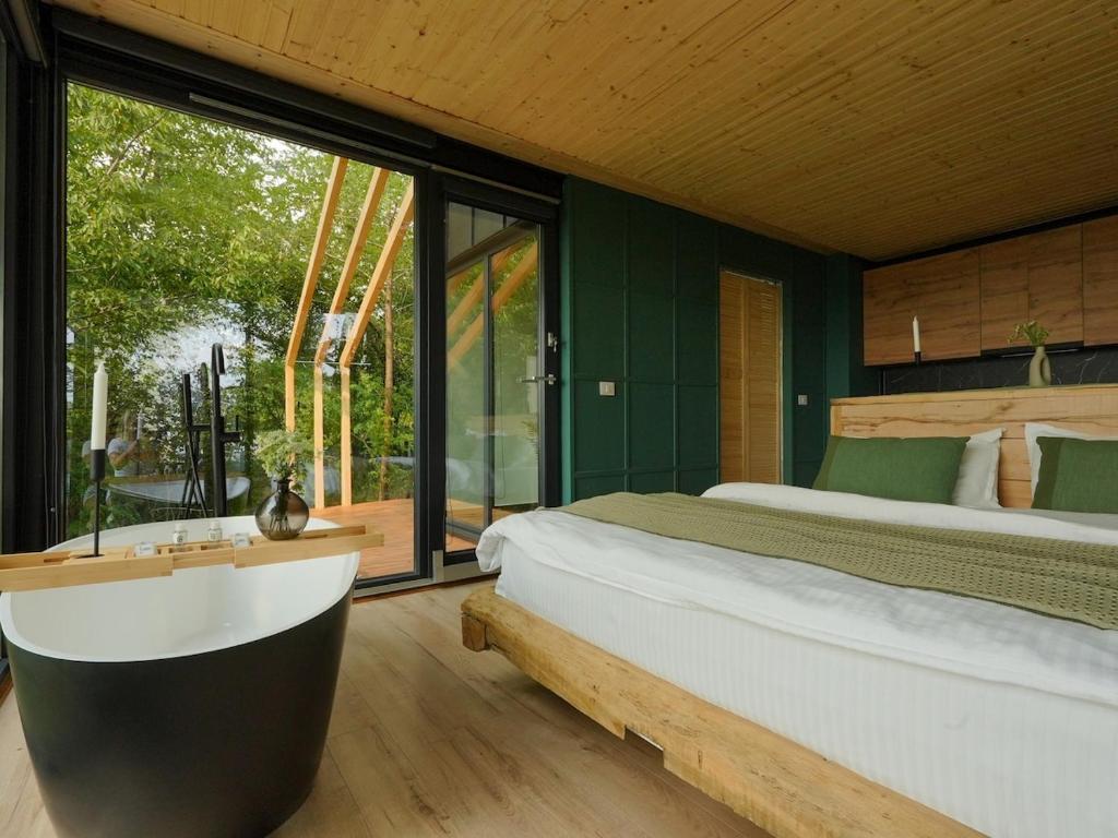 a bedroom with a large bed and a tub in it at ForestView 1- Romantic Cabin for 2 in Fuereşti