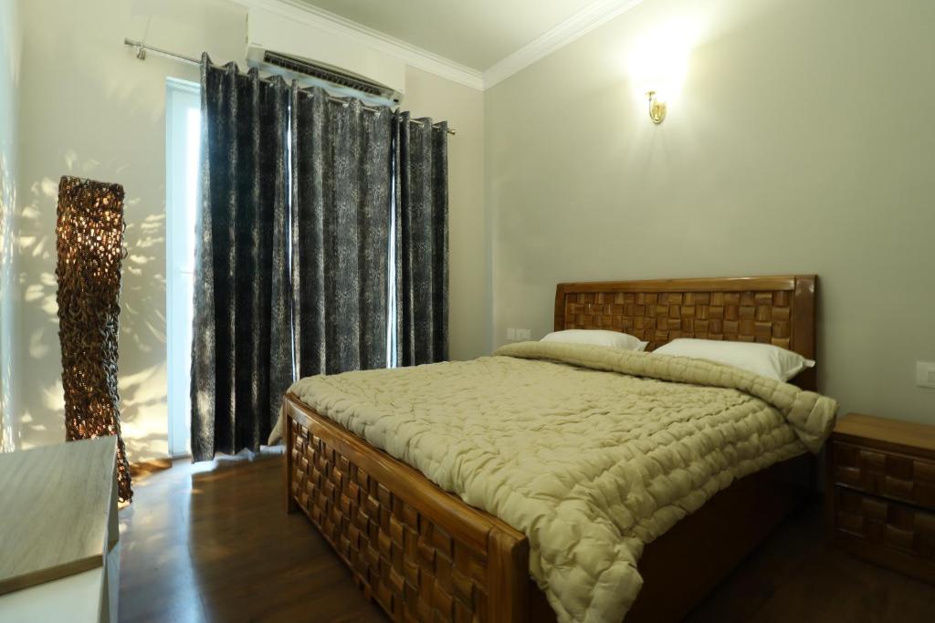 a bedroom with a large bed and a window at Central Park 2BR Apt Near Gurugram Wid pool Access in Sohna